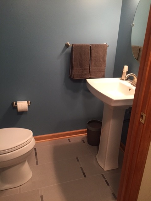 Inredning av ett klassiskt toalett, med ett piedestal handfat, en toalettstol med separat cisternkåpa, grå kakel, porslinskakel, blå väggar och klinkergolv i porslin