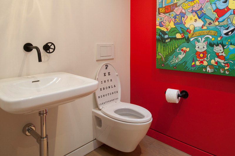This is an example of a modern cloakroom in San Francisco with a pedestal sink, a wall mounted toilet and light hardwood flooring.