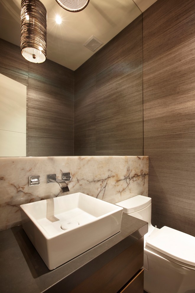 Свежая идея для дизайна: туалет в стиле модернизм с плоскими фасадами, унитазом-моноблоком, бежевой плиткой, коричневыми стенами, настольной раковиной и темными деревянными фасадами - отличное фото интерьера