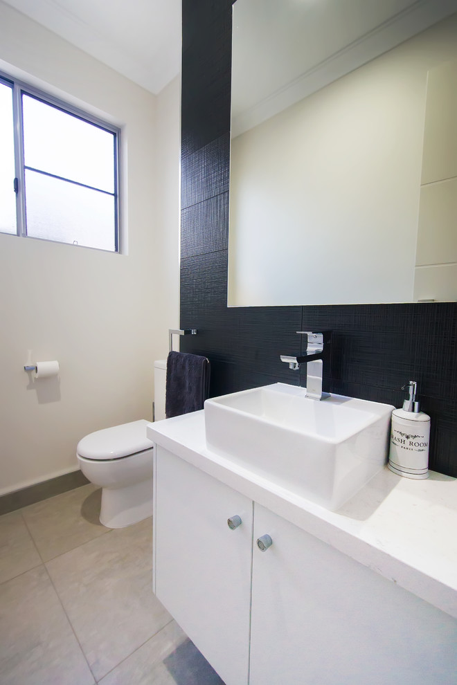 This is an example of a large contemporary cloakroom in Other with a vessel sink, flat-panel cabinets, white cabinets, black tiles, ceramic tiles, white walls, a one-piece toilet, ceramic flooring, granite worktops, grey floors, white worktops and a floating vanity unit.