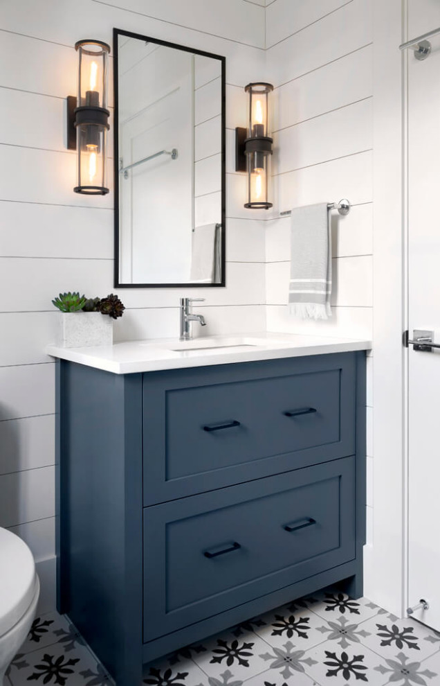 Photo of a small rural cloakroom in Vancouver with shaker cabinets, blue cabinets, white tiles, ceramic tiles, cement flooring, engineered stone worktops, white worktops, a one-piece toilet and a submerged sink.