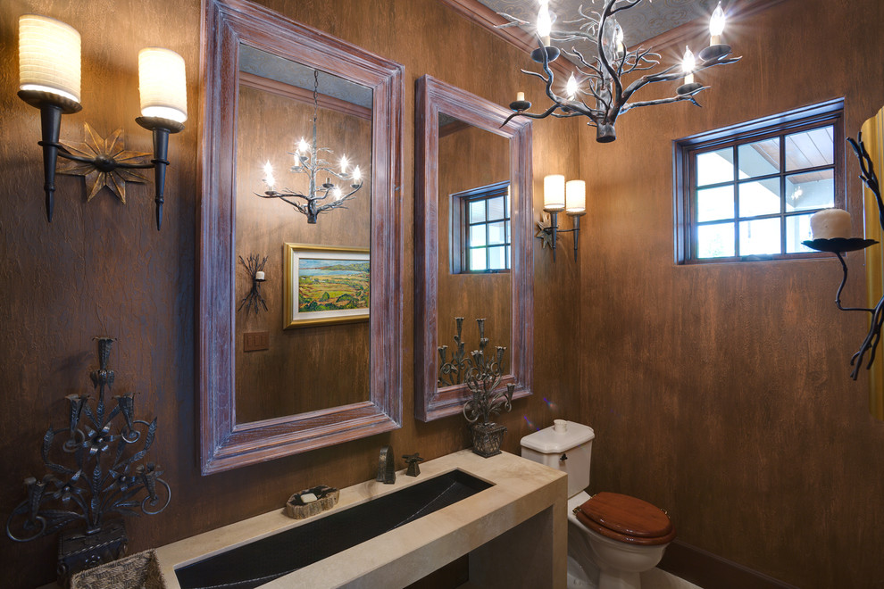 Пример оригинального дизайна: туалет в средиземноморском стиле с раковиной с несколькими смесителями, столешницей из бетона, унитазом-моноблоком, коричневыми стенами и полом из керамической плитки