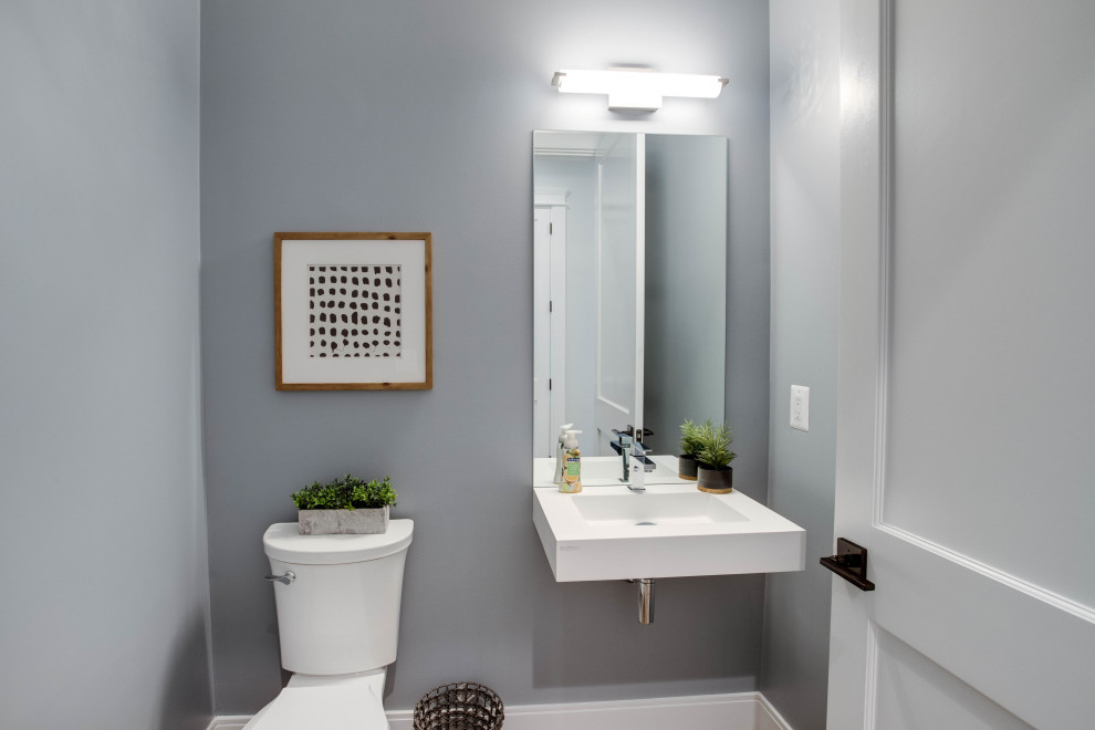 Réalisation d'un WC et toilettes minimaliste de taille moyenne avec WC séparés, un mur gris, un lavabo suspendu et un plan de toilette blanc.