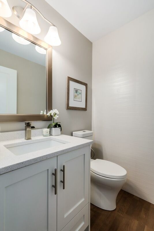 Mittelgroße Klassische Gästetoilette mit Schrankfronten im Shaker-Stil, weißen Schränken, Toilette mit Aufsatzspülkasten, weißen Fliesen, Keramikfliesen, grauer Wandfarbe, braunem Holzboden, Unterbauwaschbecken und Quarzwerkstein-Waschtisch in Vancouver