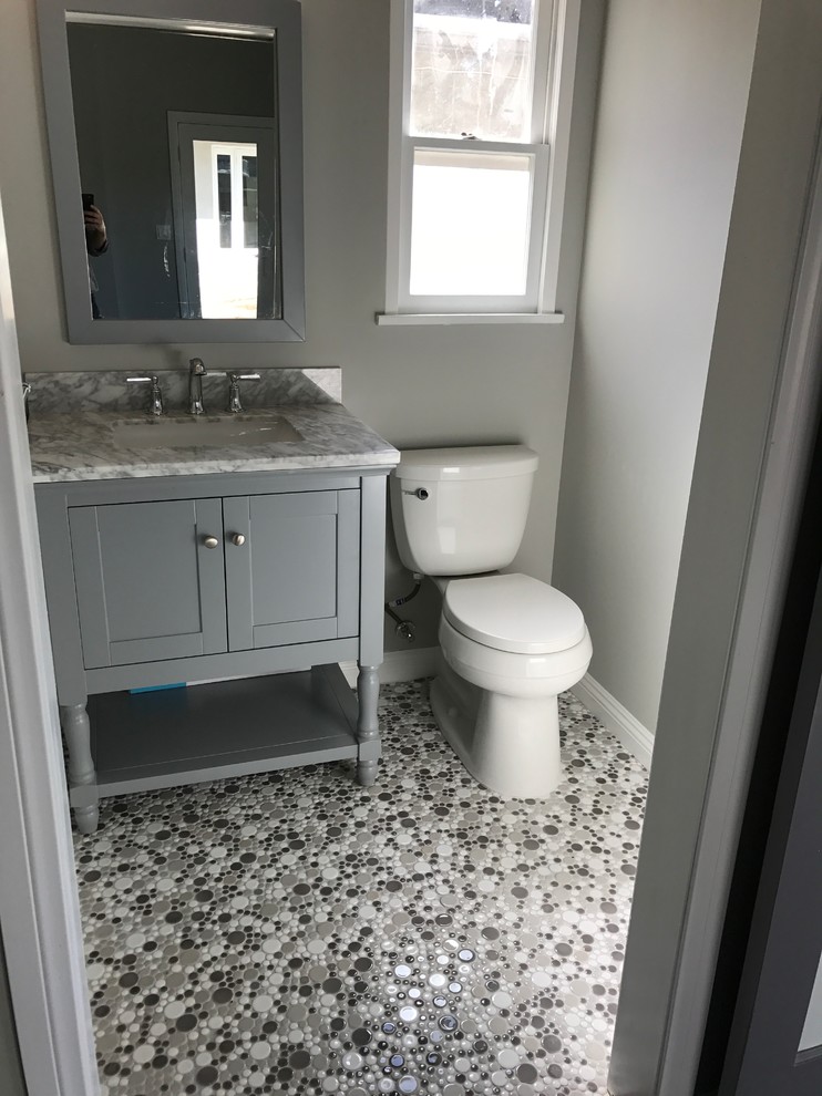 Exemple d'un WC et toilettes chic de taille moyenne avec un placard à porte shaker, des portes de placard grises, WC séparés, un carrelage gris, un mur blanc, un sol en galet, un lavabo encastré, un plan de toilette en marbre, un sol multicolore et un plan de toilette gris.