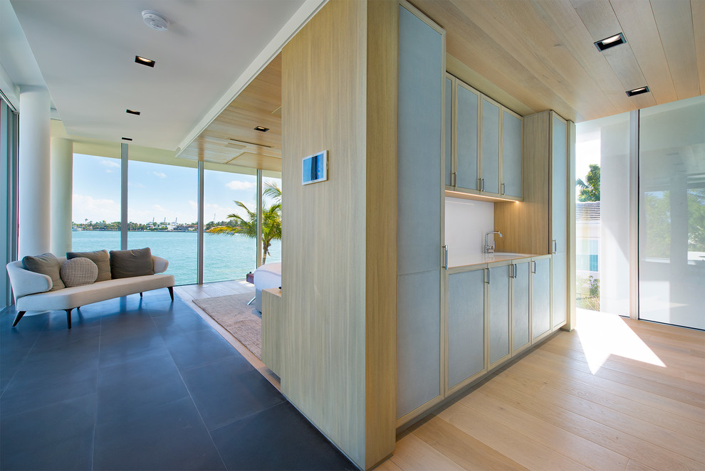 Geräumige Moderne Gästetoilette mit flächenbündigen Schrankfronten, blauen Schränken, hellem Holzboden, integriertem Waschbecken, beigem Boden, weißer Waschtischplatte und Edelstahl-Waschbecken/Waschtisch in Miami