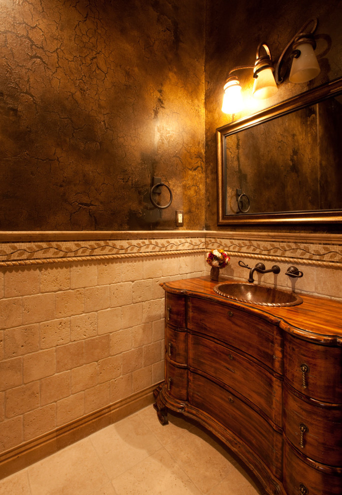 Powder room - small mediterranean beige tile and terra-cotta tile marble floor and beige floor powder room idea in Las Vegas with furniture-like cabinets, medium tone wood cabinets, brown walls, a drop-in sink, wood countertops and brown countertops