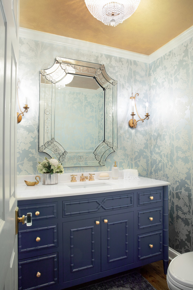 Ispirazione per un bagno di servizio tradizionale con consolle stile comò, ante blu, pareti multicolore, parquet scuro, lavabo sottopiano e top bianco