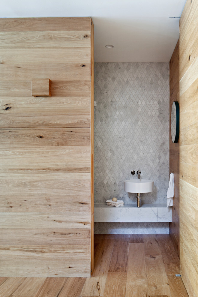 Exempel på ett mellanstort klassiskt grå grått toalett, med grå skåp, en vägghängd toalettstol, grå kakel, marmorkakel, vita väggar, ett väggmonterat handfat och marmorbänkskiva