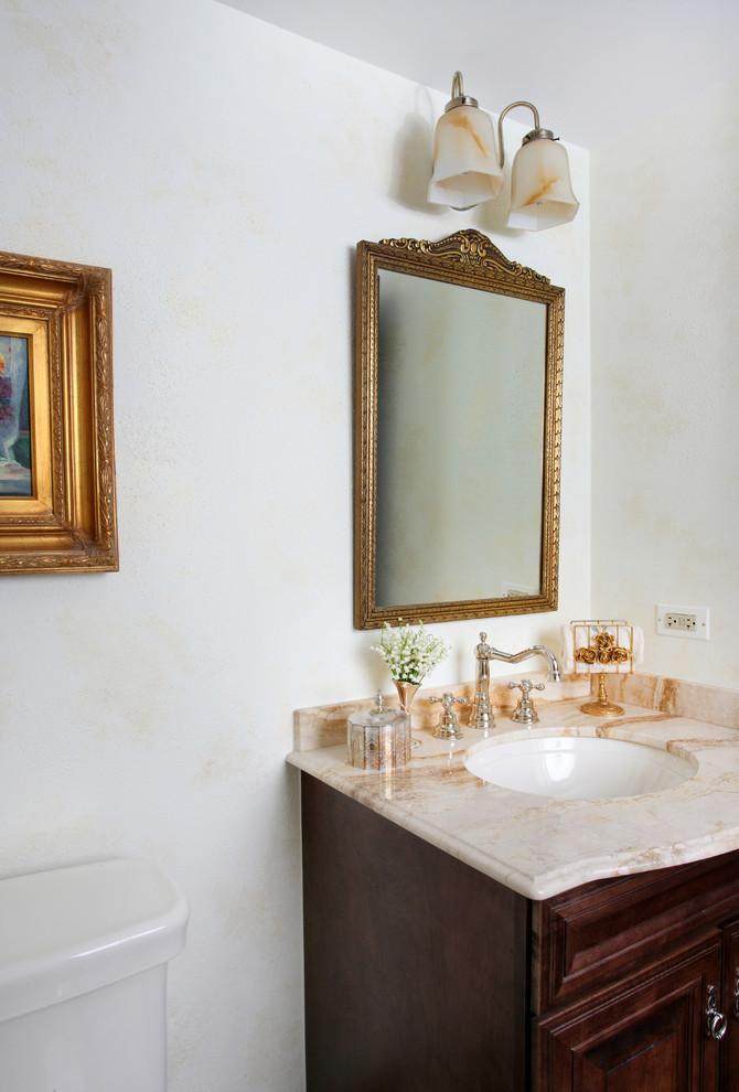 Idee per un piccolo bagno di servizio classico con lavabo sottopiano, ante con bugna sagomata, ante in legno bruno, top in marmo e pareti bianche