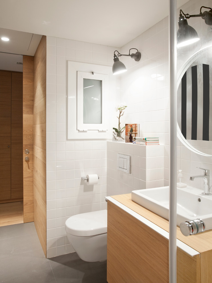 Design ideas for a medium sized contemporary cloakroom in Barcelona with flat-panel cabinets, medium wood cabinets, a wall mounted toilet and a submerged sink.