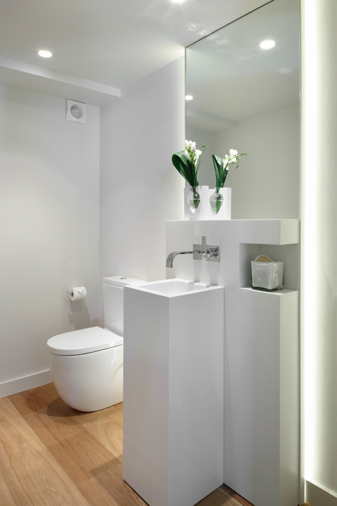 Idee per un bagno di servizio contemporaneo di medie dimensioni con WC a due pezzi, pareti bianche, pavimento in legno massello medio e lavabo a colonna