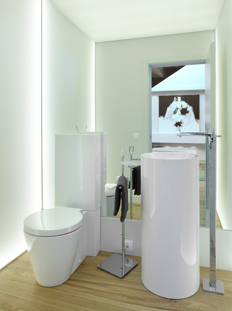 Kleine Moderne Gästetoilette mit Wandtoilette mit Spülkasten, weißer Wandfarbe, braunem Holzboden und Sockelwaschbecken in Barcelona