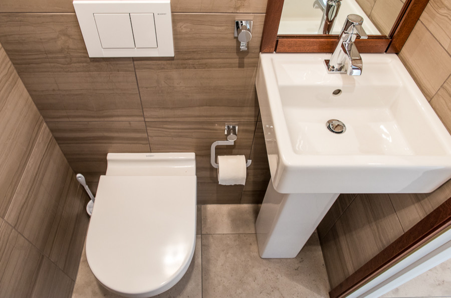 Bild på ett mellanstort funkis toalett, med en vägghängd toalettstol, beige väggar, beiget golv, beige kakel, porslinskakel, klinkergolv i keramik och ett piedestal handfat