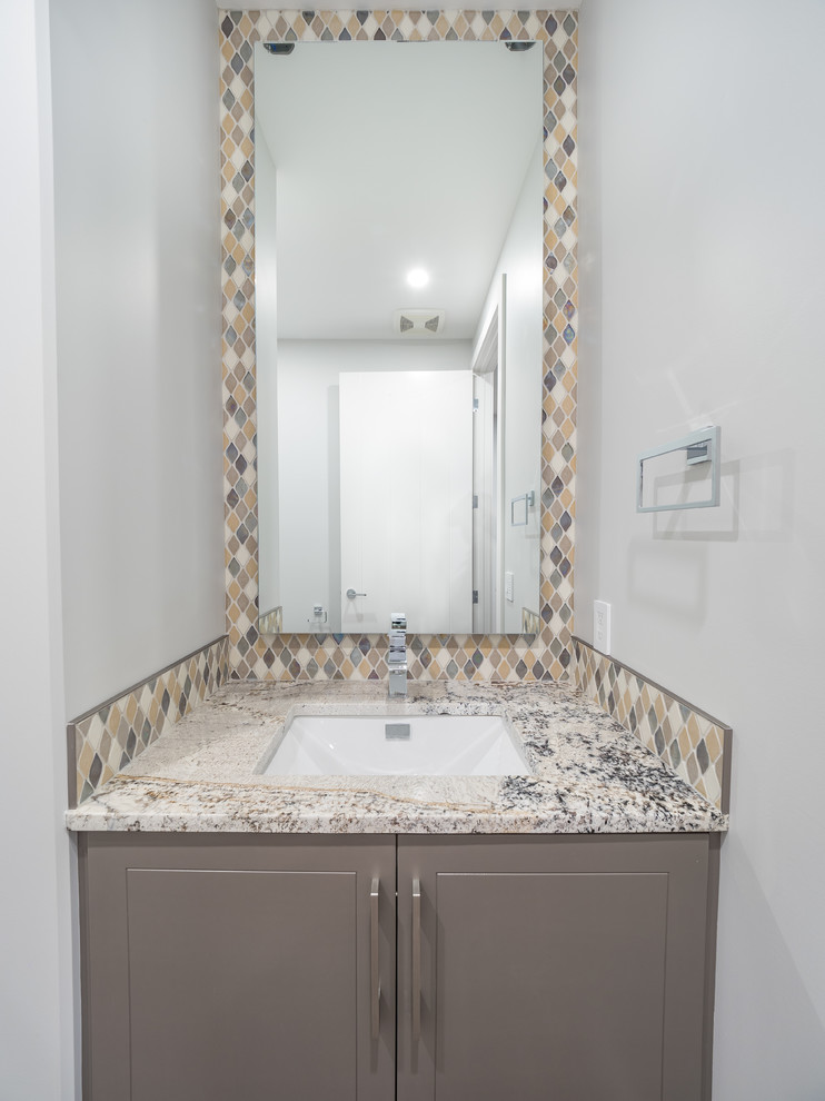 Photo of a medium sized contemporary cloakroom in Edmonton with beaded cabinets, grey cabinets, multi-coloured tiles, stone tiles, quartz worktops, a two-piece toilet, grey walls, vinyl flooring, a built-in sink and multi-coloured floors.
