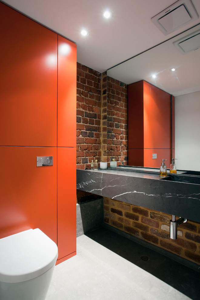 パースにある中くらいなインダストリアルスタイルのおしゃれなトイレ・洗面所 (一体型シンク、フラットパネル扉のキャビネット、オレンジのキャビネット、大理石の洗面台) の写真