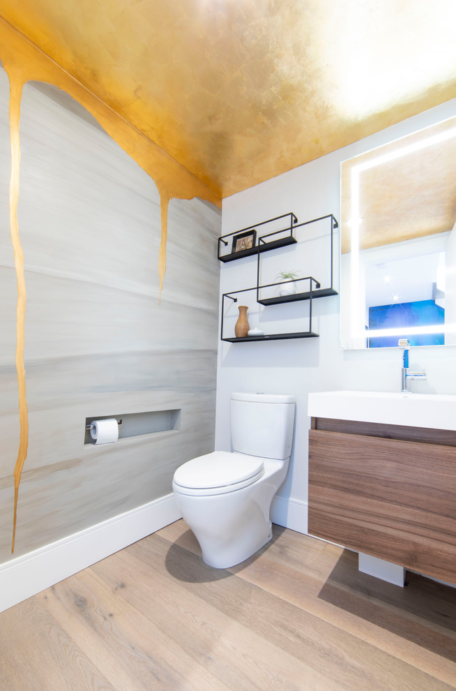 Mittelgroße Moderne Gästetoilette mit flächenbündigen Schrankfronten, hellbraunen Holzschränken, Toilette mit Aufsatzspülkasten, hellem Holzboden, Waschtischkonsole, beigem Boden, weißer Waschtischplatte und grauer Wandfarbe in Toronto
