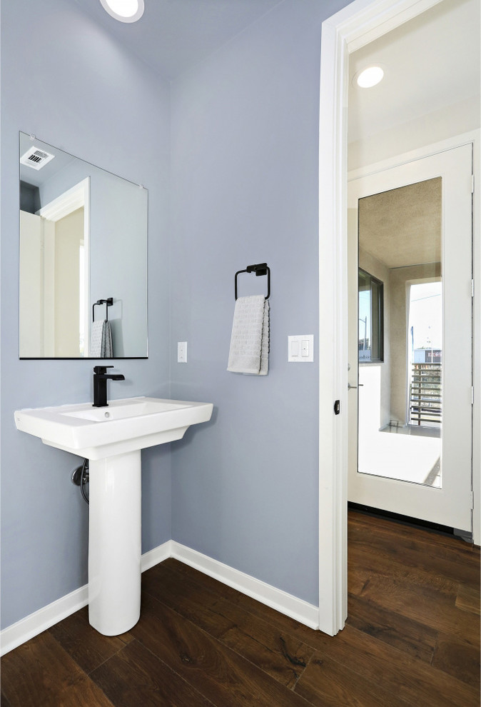 Imagen de aseo clásico renovado con paredes azules, suelo de madera en tonos medios, lavabo con pedestal y suelo marrón