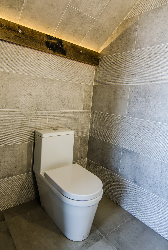 На фото: маленький туалет в современном стиле с подвесной раковиной, унитазом-моноблоком, серой плиткой, керамогранитной плиткой, серыми стенами и полом из керамогранита для на участке и в саду с
