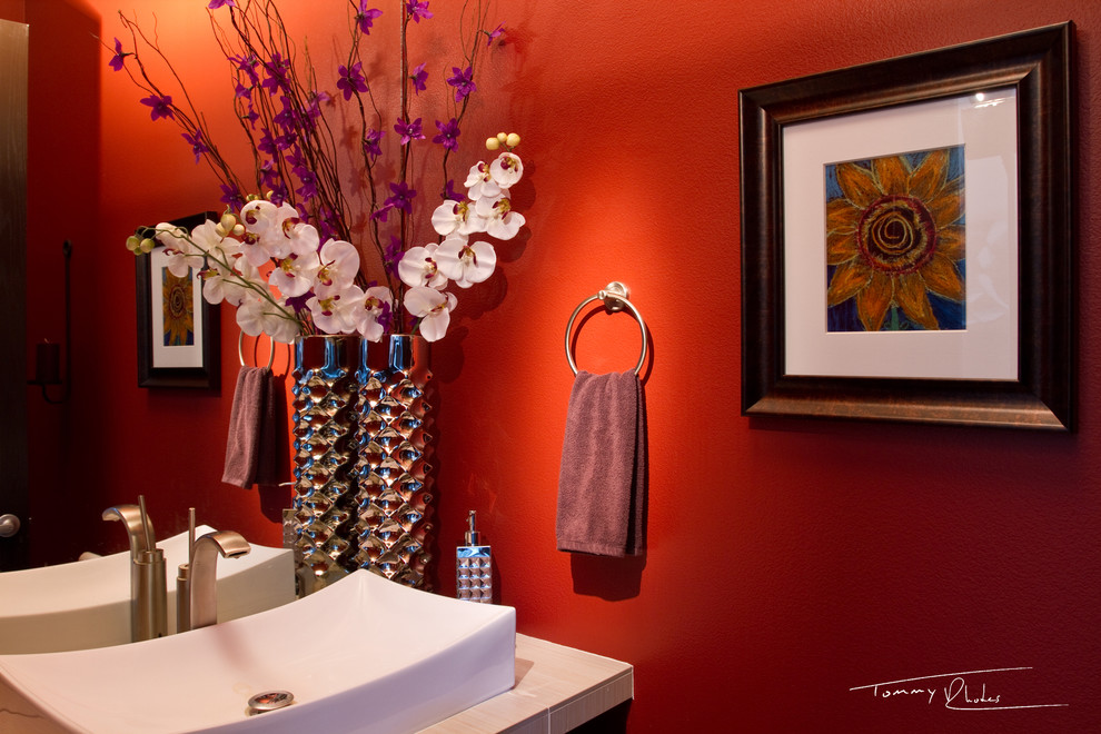 Foto de aseo contemporáneo pequeño con lavabo sobreencimera, armarios con paneles lisos, puertas de armario de madera en tonos medios, encimera de azulejos, sanitario de una pieza y paredes rojas