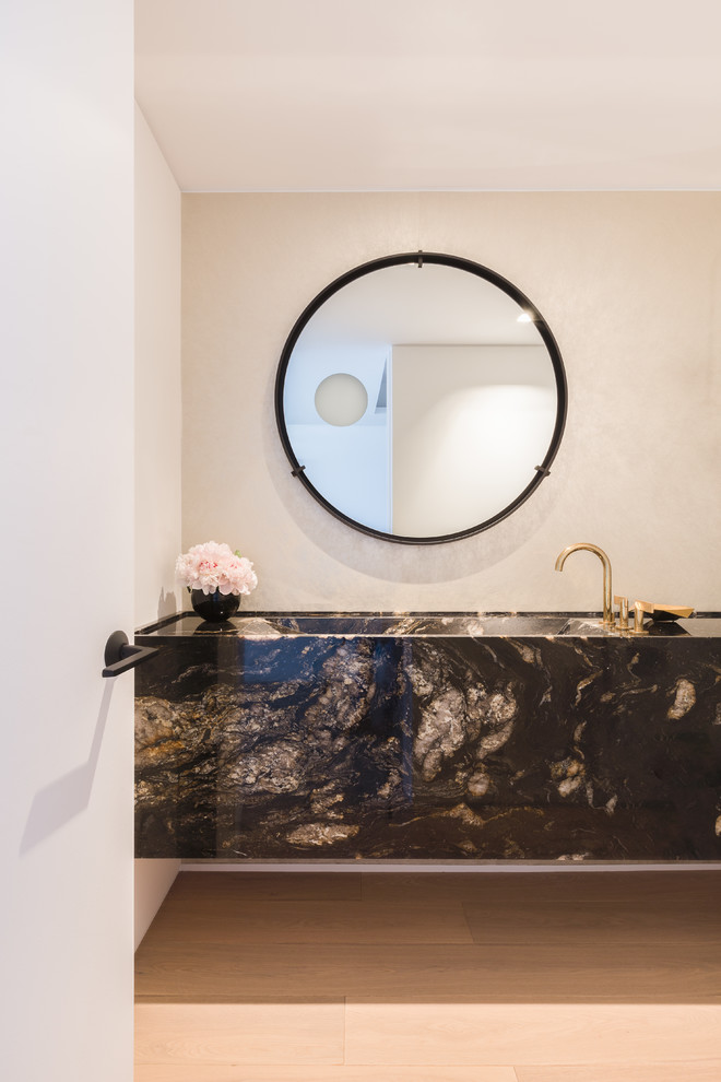 Immagine di un bagno di servizio minimal di medie dimensioni con consolle stile comò, ante grigie, WC monopezzo, pareti bianche, parquet chiaro, lavabo integrato e top in granito