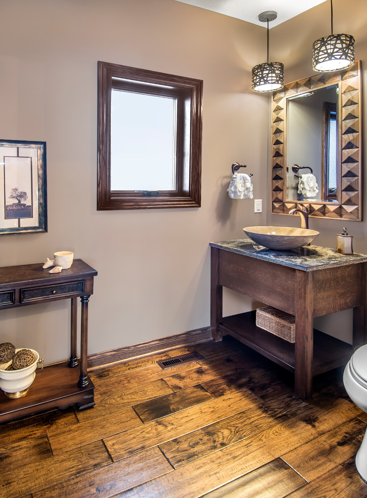 Moderne Gästetoilette mit Aufsatzwaschbecken, verzierten Schränken, dunklen Holzschränken, Granit-Waschbecken/Waschtisch, beiger Wandfarbe und braunem Holzboden in Sonstige