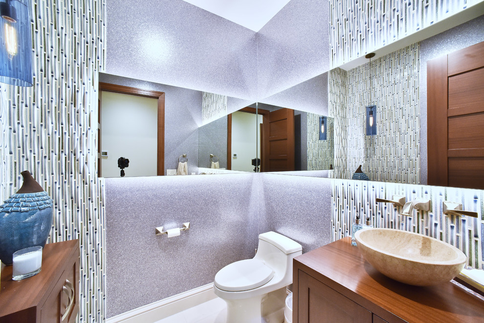 Photo of a medium sized contemporary cloakroom in Baltimore with shaker cabinets, white cabinets, a one-piece toilet, multi-coloured tiles, matchstick tiles, purple walls, a vessel sink, wooden worktops, limestone flooring and beige floors.