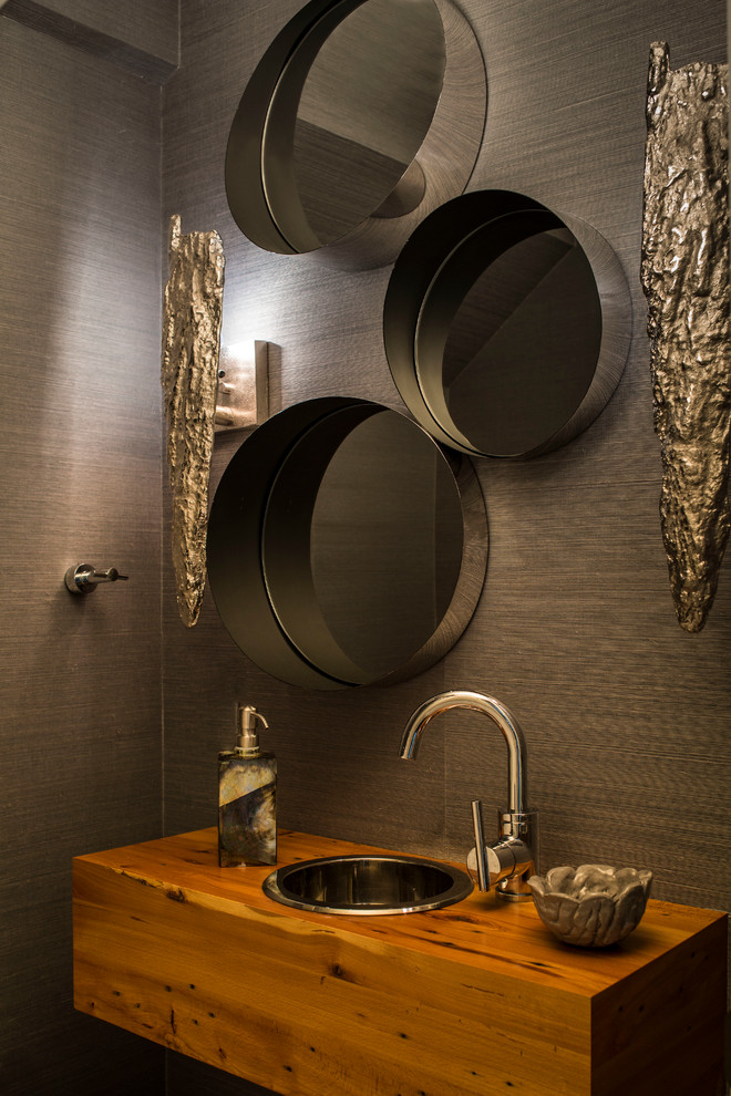 Idée de décoration pour un WC et toilettes design avec un lavabo posé, un plan de toilette en bois, un mur marron et un plan de toilette marron.