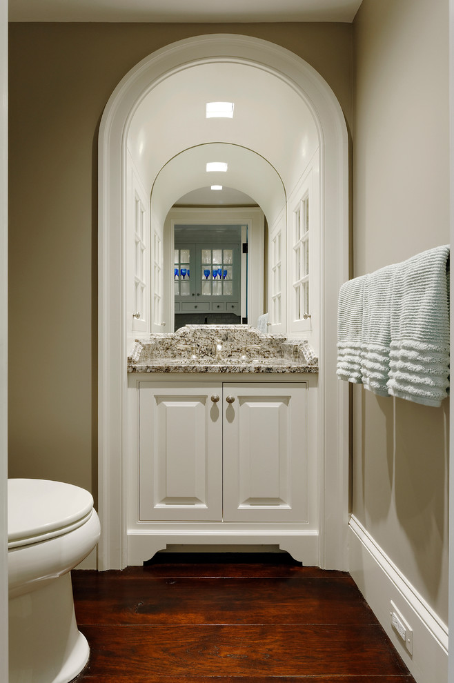 Exempel på ett litet klassiskt toalett, med luckor med upphöjd panel, vita skåp, beige väggar, mörkt trägolv, ett undermonterad handfat och granitbänkskiva