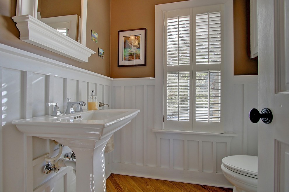 Mittelgroße Maritime Gästetoilette mit Toilette mit Aufsatzspülkasten, beiger Wandfarbe, hellem Holzboden, Sockelwaschbecken und braunem Boden in Charleston