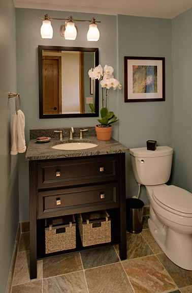Réalisation d'un WC et toilettes tradition de taille moyenne avec un lavabo encastré, des portes de placard noires, un plan de toilette en granite, WC séparés, un mur bleu et un sol en carrelage de céramique.