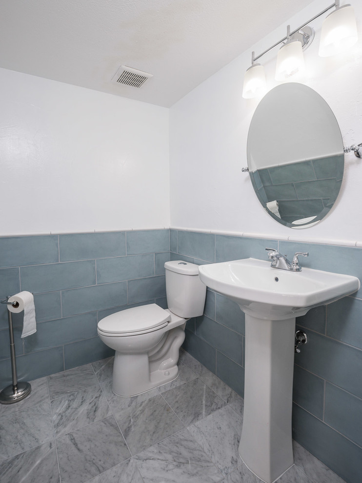 Réalisation d'un WC et toilettes minimaliste de taille moyenne avec WC séparés, un carrelage bleu, des carreaux de porcelaine, un mur blanc, un sol en marbre, un lavabo de ferme, un sol blanc, des portes de placard blanches et meuble-lavabo encastré.