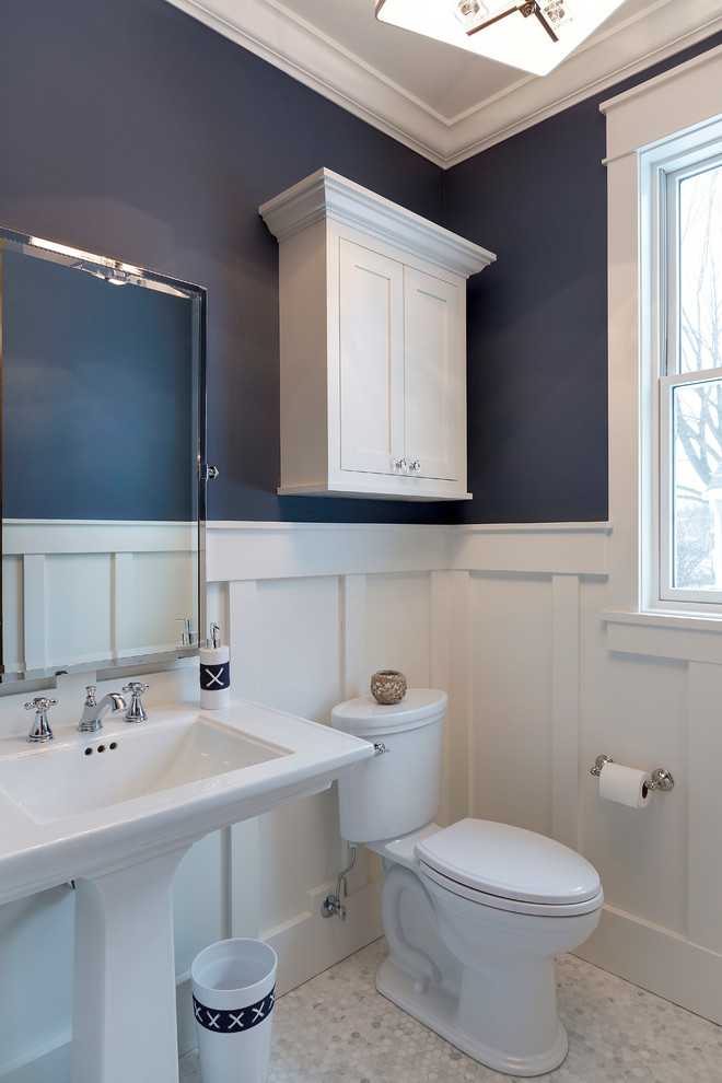 Inredning av ett klassiskt toalett, med vita skåp, blå väggar och marmorgolv