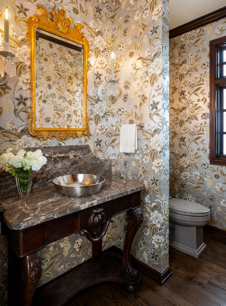 Inspiration for a timeless dark wood floor and wallpaper powder room remodel in Minneapolis with dark wood cabinets, a one-piece toilet, multicolored walls, a drop-in sink, quartzite countertops, gray countertops and a freestanding vanity