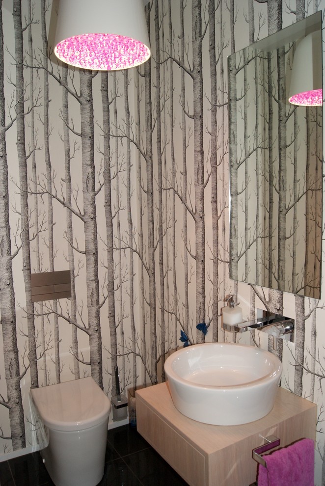 Esempio di un piccolo bagno di servizio moderno con ante lisce, ante in legno chiaro, WC monopezzo, pareti multicolore, pavimento in gres porcellanato, lavabo a bacinella, top in legno, pavimento nero e top bianco