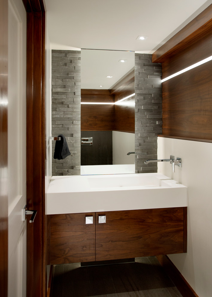 Réalisation d'un petit WC et toilettes design en bois brun avec un placard à porte plane, un mur blanc, un sol en ardoise, un lavabo intégré et un plan de toilette en quartz modifié.