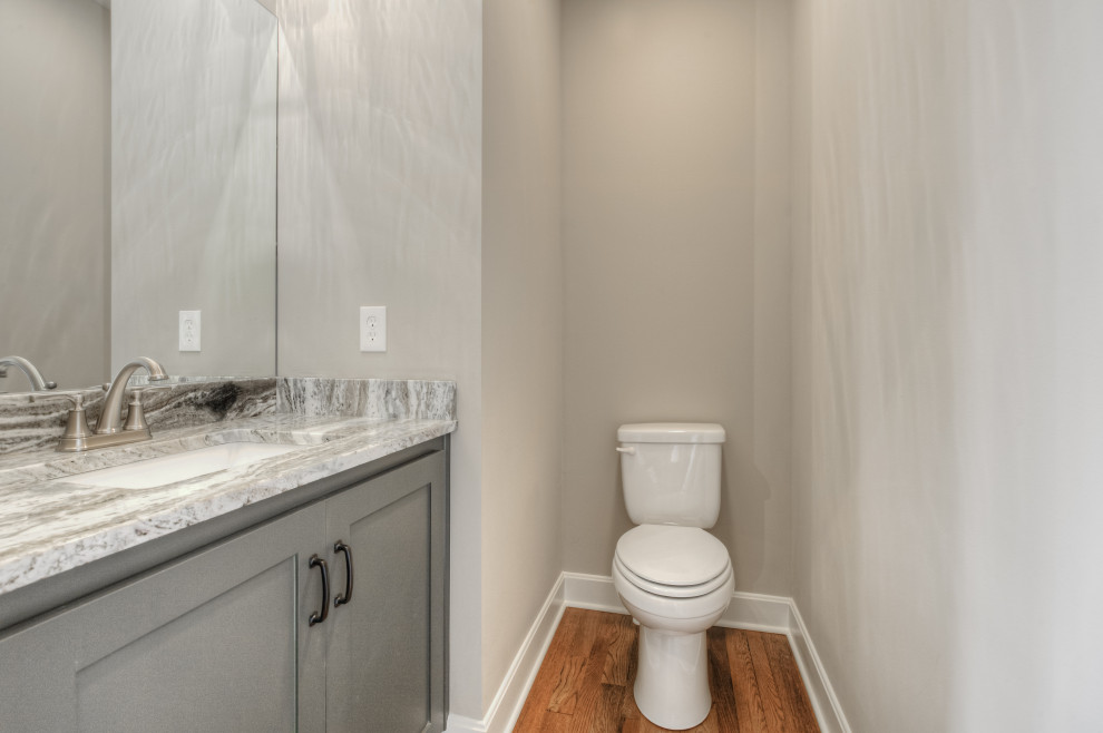 Small classic cloakroom in Kansas City with shaker cabinets, grey cabinets, beige walls, medium hardwood flooring, a submerged sink, granite worktops, brown floors, multi-coloured worktops and a built in vanity unit.
