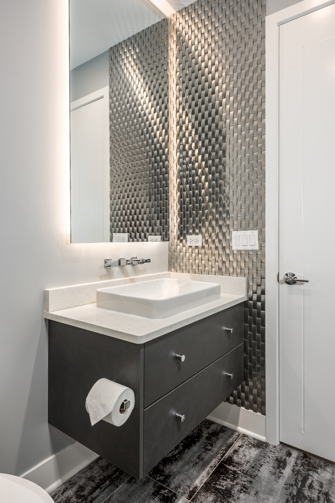 Example of a mid-sized minimalist ceramic tile gray floor and ceramic tile powder room design in Chicago with flat-panel cabinets, gray cabinets, a two-piece toilet, gray walls, a trough sink, a floating vanity, white countertops and quartz countertops