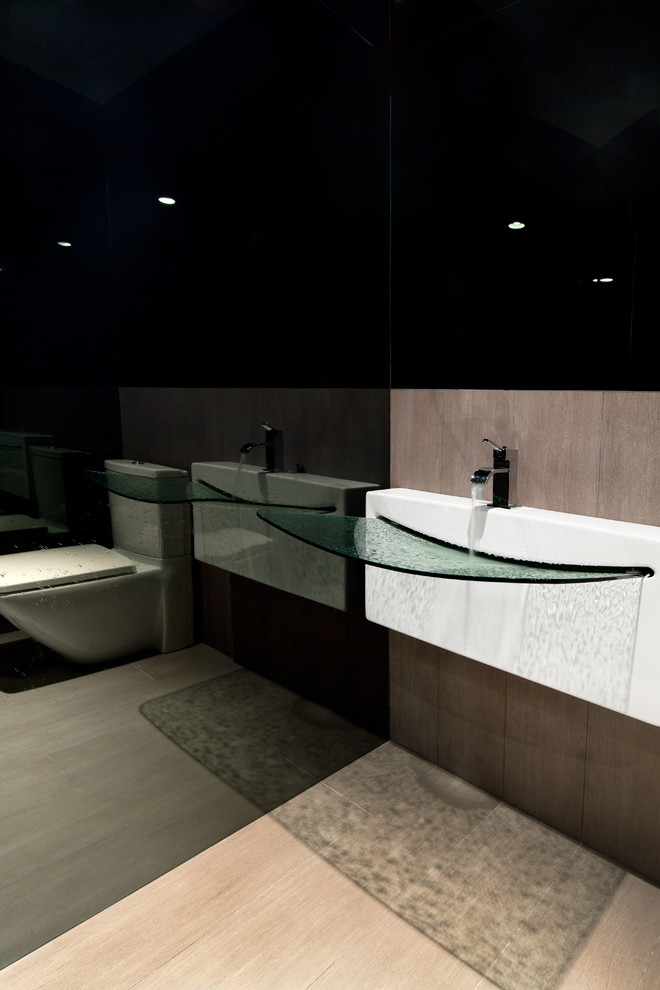 Exemple d'un petit WC et toilettes tendance avec un carrelage gris, des carreaux de porcelaine, un mur gris, un sol en carrelage de porcelaine, WC séparés et un lavabo suspendu.