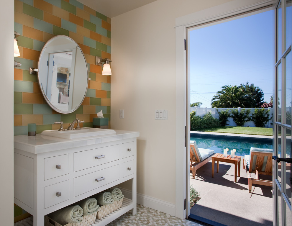 Klassische Gästetoilette mit Einbauwaschbecken, flächenbündigen Schrankfronten, weißen Schränken, farbigen Fliesen, beiger Wandfarbe und weißer Waschtischplatte in San Diego