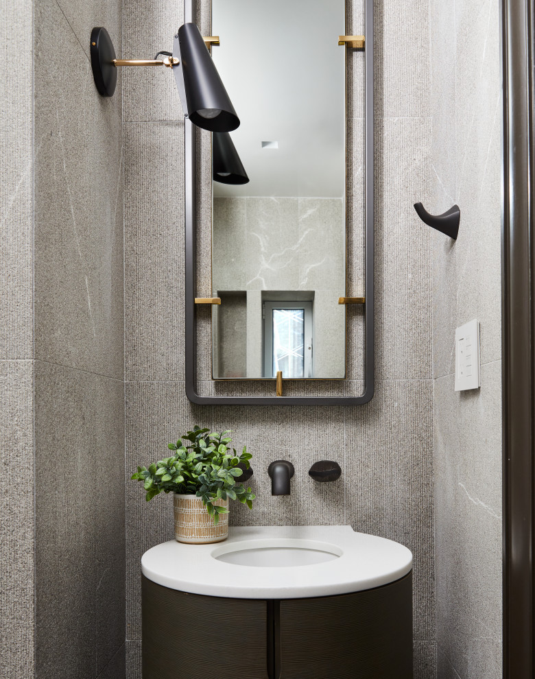This is an example of a contemporary cloakroom in New York with flat-panel cabinets, dark wood cabinets, grey tiles, a submerged sink and white worktops.