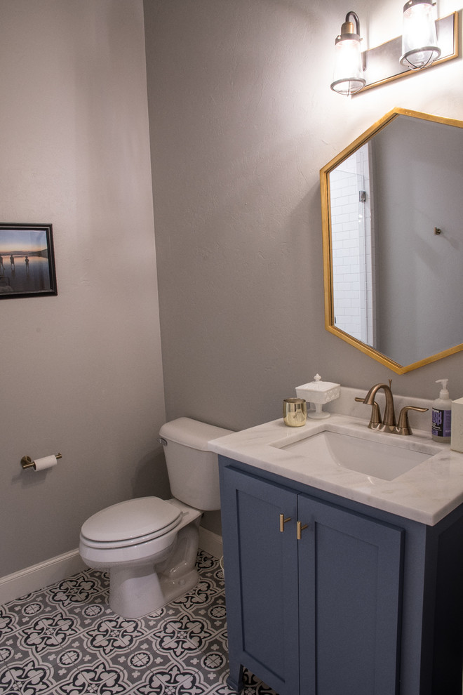 Cette image montre un grand WC et toilettes traditionnel avec un placard à porte shaker, des portes de placard bleues, un carrelage gris, un mur gris, un sol en carrelage de terre cuite, un lavabo encastré, un plan de toilette en quartz et un sol gris.