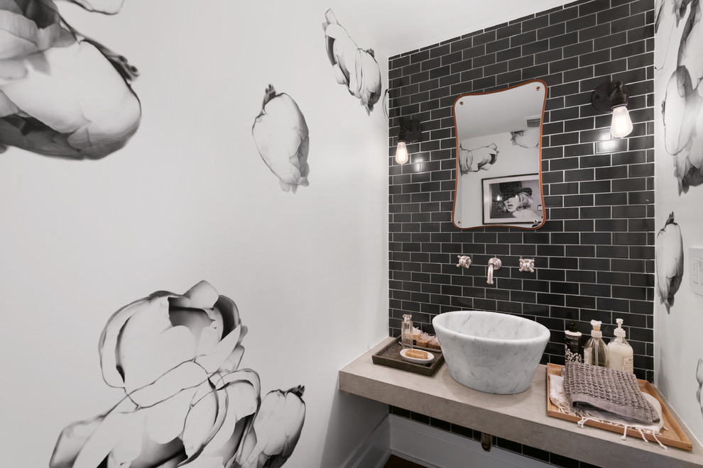 ニューヨークにある小さなトランジショナルスタイルのおしゃれなトイレ・洗面所 (黒いタイル、マルチカラーの壁、ベッセル式洗面器、ライムストーンの洗面台、サブウェイタイル) の写真