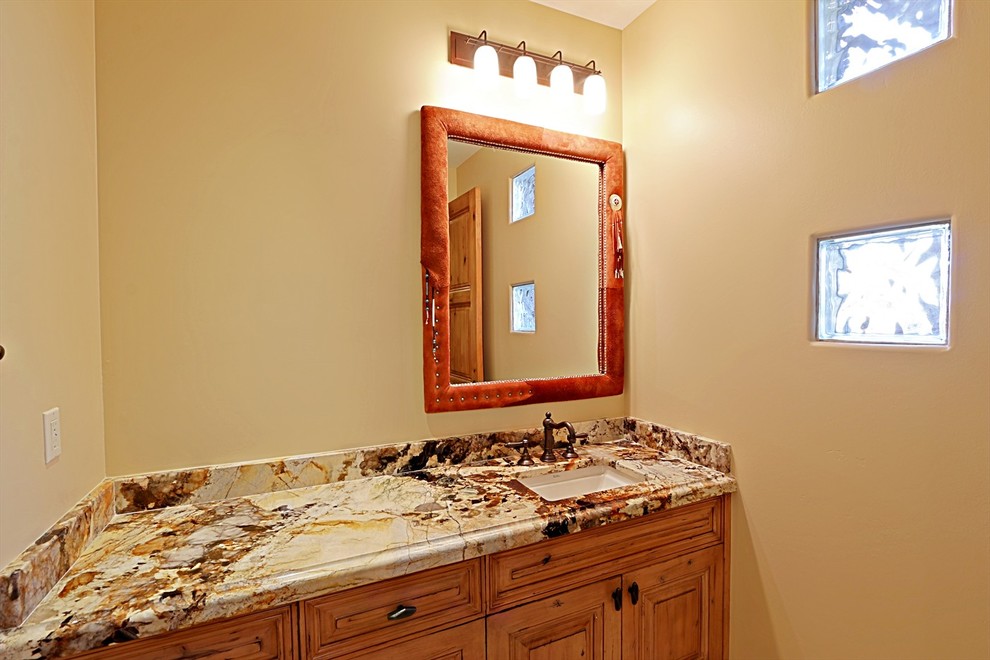 Mediterrane Gästetoilette mit profilierten Schrankfronten, hellbraunen Holzschränken, beiger Wandfarbe, Unterbauwaschbecken und Granit-Waschbecken/Waschtisch in Phoenix