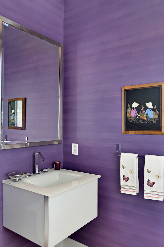 Réalisation d'un petit WC et toilettes design avec un mur violet, un placard à porte plane, des portes de placard blanches, un lavabo intégré et un plan de toilette en verre.