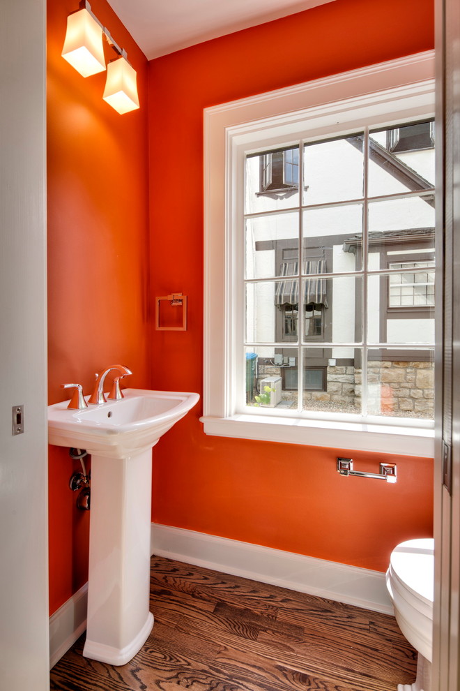 Idee per un piccolo bagno di servizio chic con lavabo a colonna, pareti arancioni e pavimento in legno massello medio