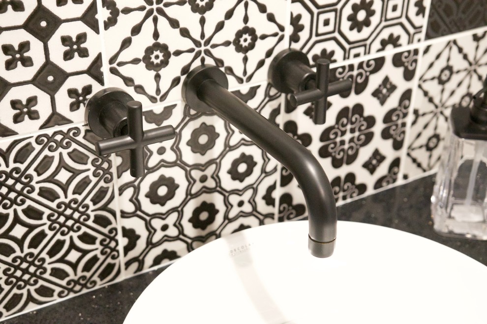 Modern inredning av ett litet svart svart toalett, med en toalettstol med separat cisternkåpa, svart och vit kakel, porslinskakel, grå väggar, vinylgolv, ett fristående handfat, bänkskiva i kvarts och svart golv
