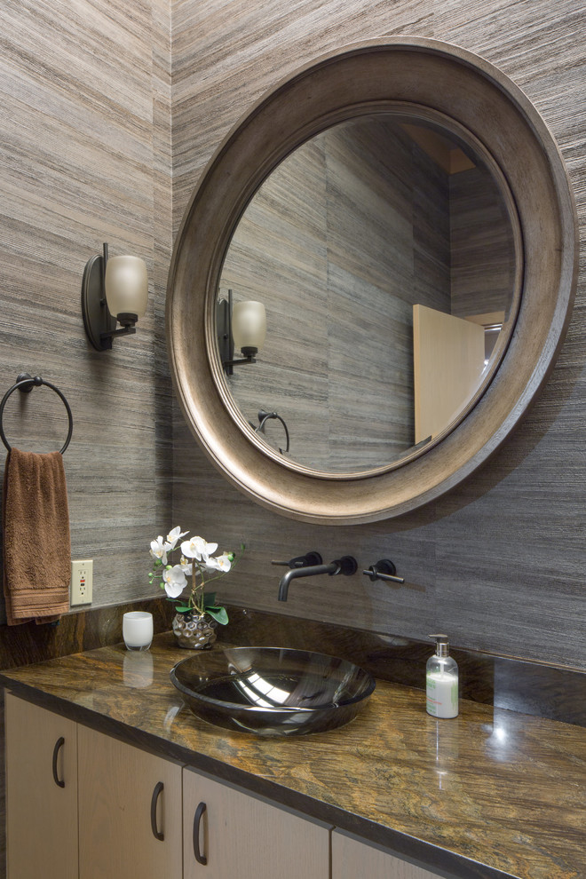 Cette image montre un WC et toilettes design en bois clair de taille moyenne avec un placard à porte plane, WC à poser, un mur marron, un sol en bois brun, une vasque, un plan de toilette en granite et un sol marron.