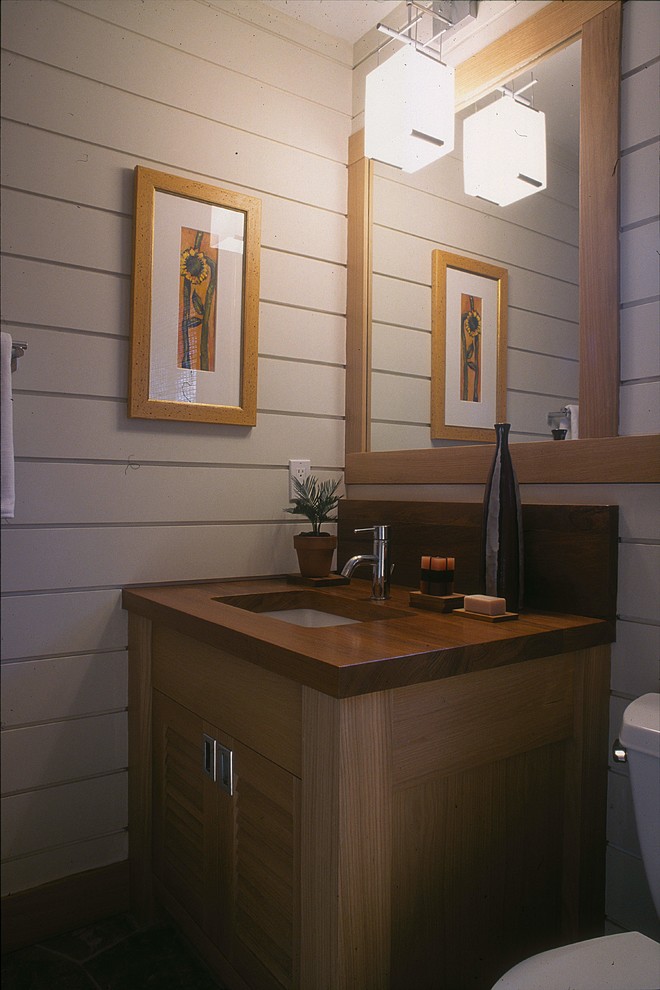 Foto de aseo actual pequeño con armarios con puertas mallorquinas, sanitario de una pieza, paredes blancas, lavabo bajoencimera, encimera de madera y puertas de armario de madera oscura