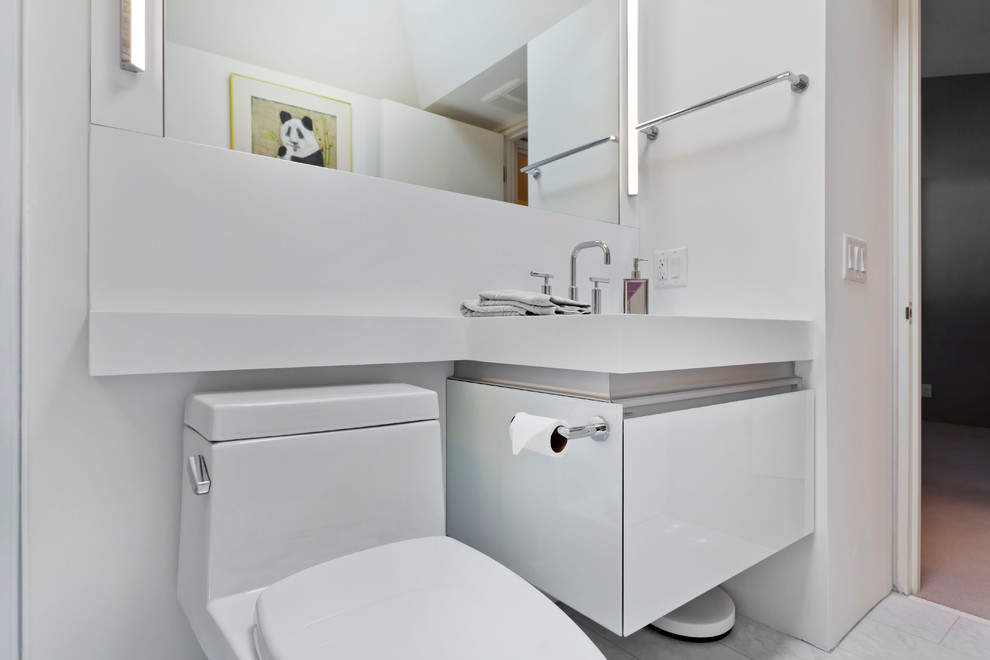 Ispirazione per un piccolo bagno di servizio design con lavabo sottopiano, ante di vetro, ante bianche, top in superficie solida, WC monopezzo, piastrelle bianche e pavimento in gres porcellanato